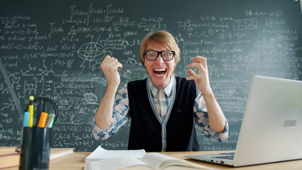 Blooket Login – A Master Guide to Gamified Classroom Success Excited man in glasses celebrating in front of blackboard.